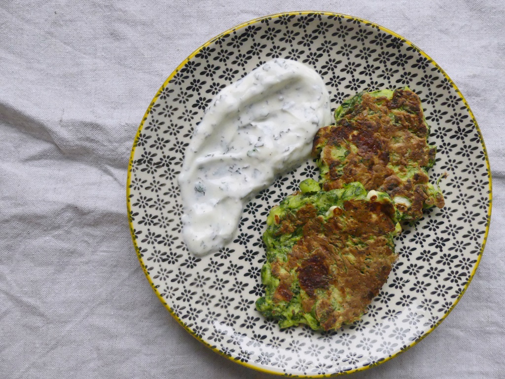 Ein Teller mit 2 Spinatpuffern und etwas Joghurtdipp