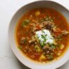 tiefer teller mit einer gemüsesuppe mit hackfleischeinlage und sauerrahm
