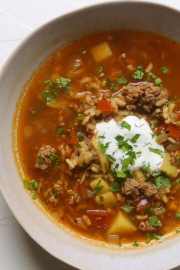 tiefer teller mit einer gemüsesuppe mit hackfleischeinlage und sauerrahm