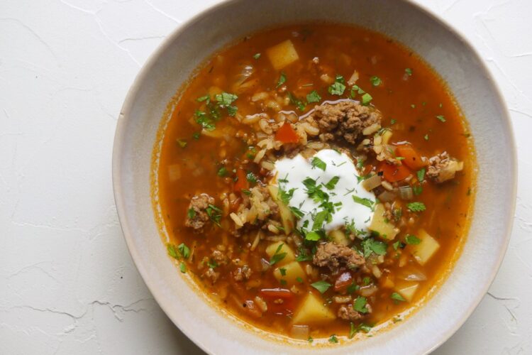 tiefer teller mit einer gemüsesuppe mit hackfleischeinlage und sauerrahm