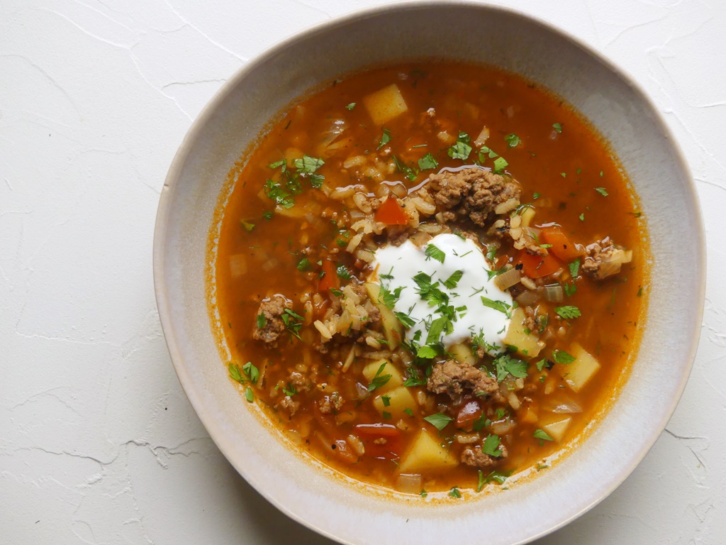 tiefer teller mit einer gemüsesuppe mit hackfleischeinlage und sauerrahm
